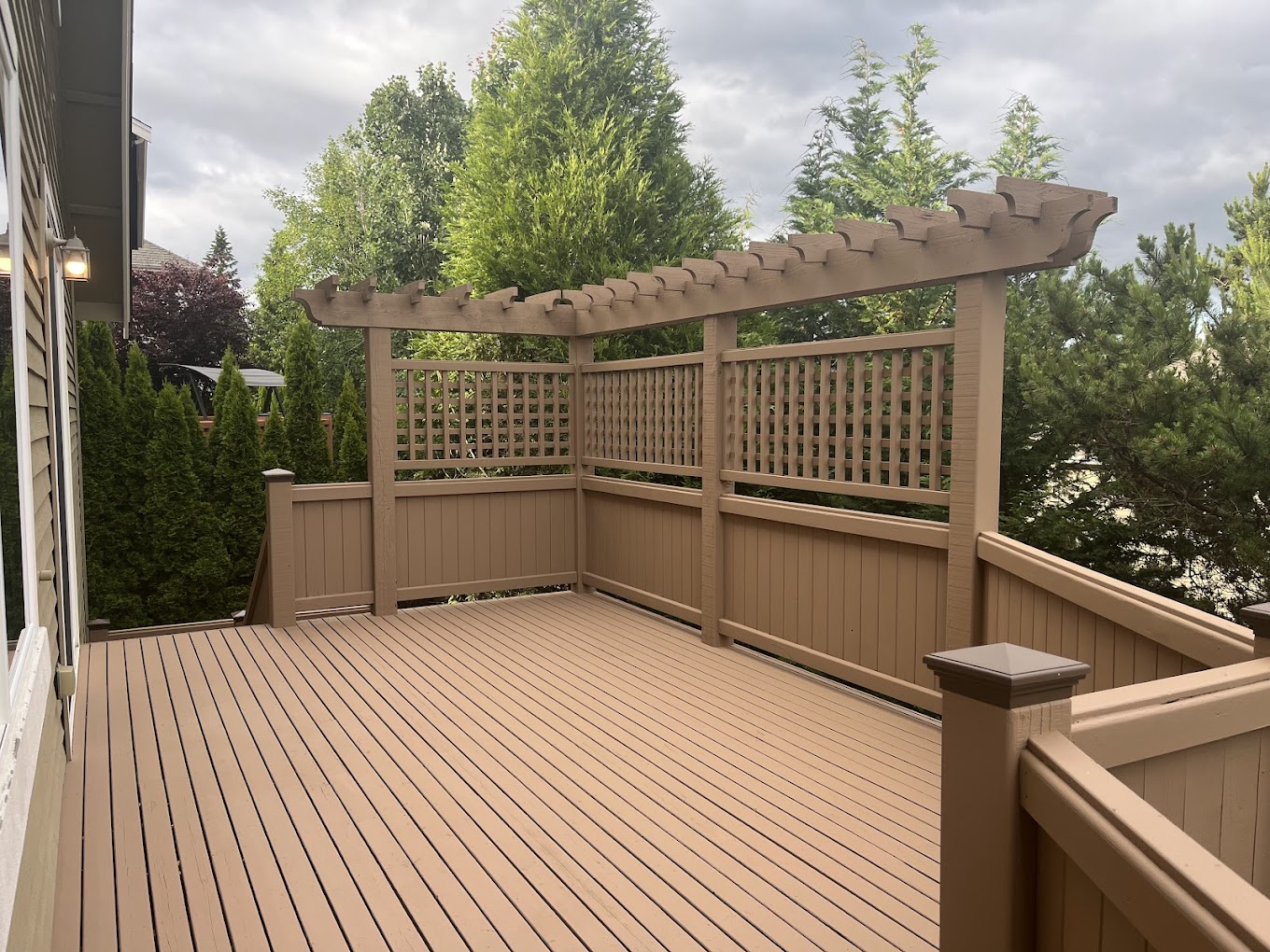 Deck painting Redmond WA — freshly painted tan deck with pergola and lattice privacy screen