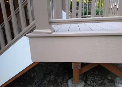 Deck painting Redmond WA — fresh tan deck boards with white skirt board and railing posts