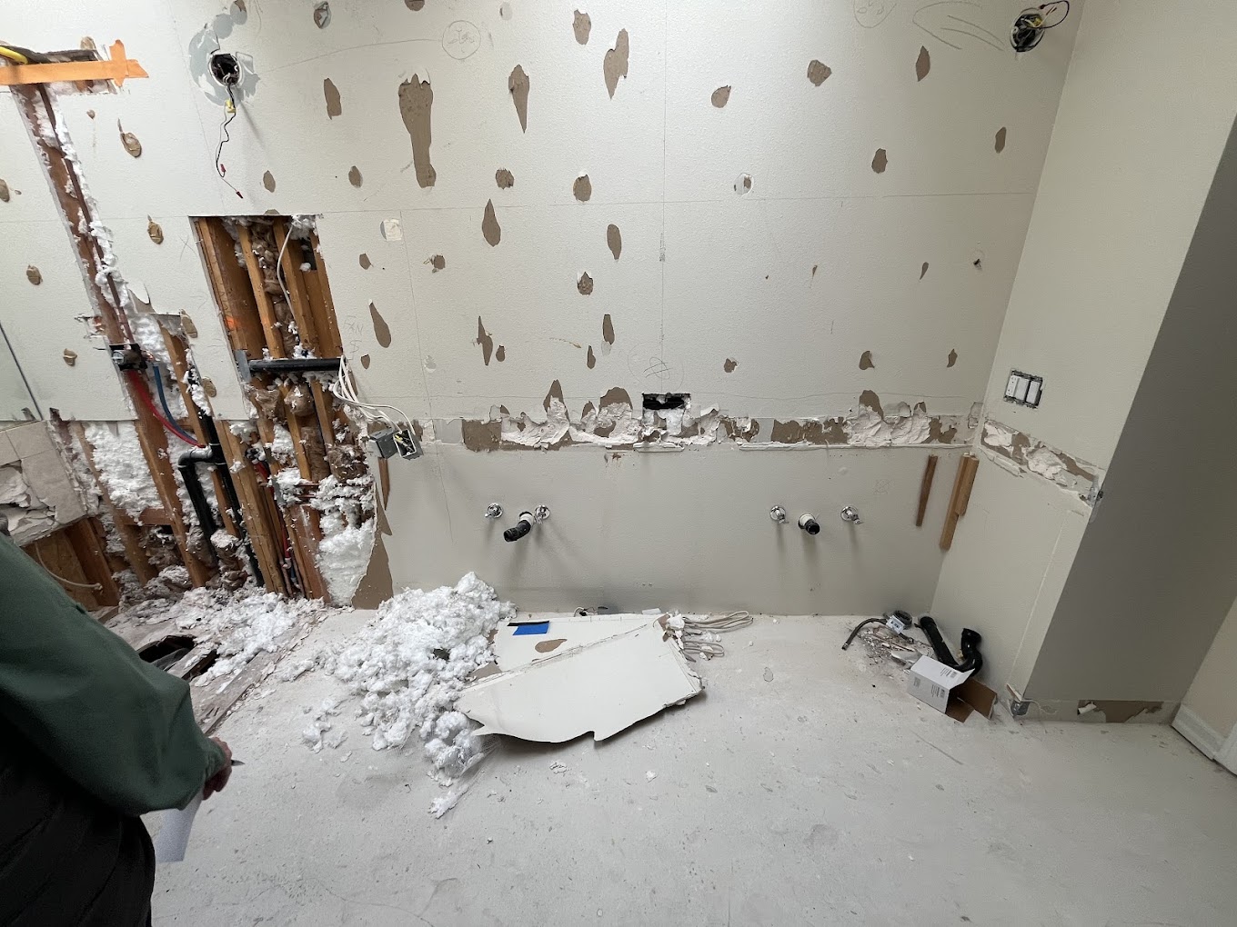 Drywall repair Redmond WA — wall demo exposing wood studs, insulation and plumbing during bathroom remodel