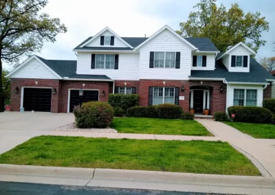Two-story exterior repaint Exterior house painting in Redmond WA — two-story brick and white siding home with manicured yard