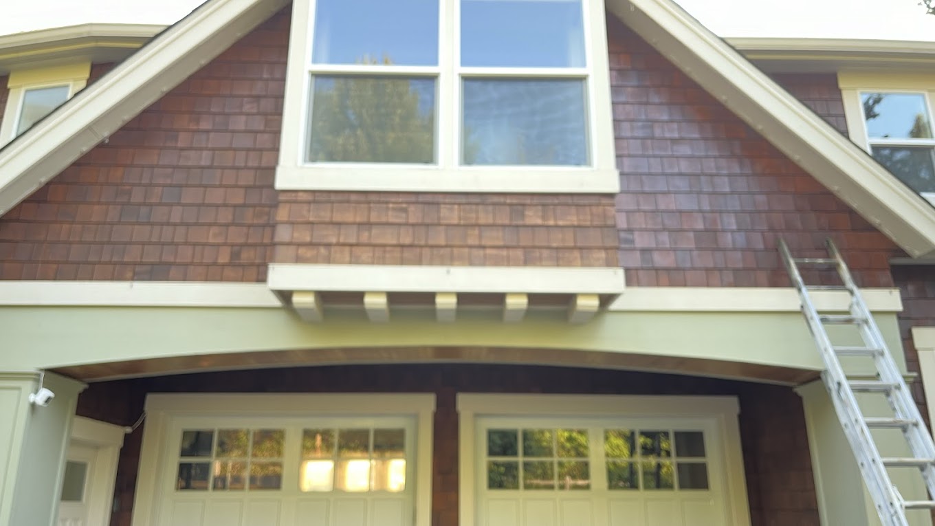 Exterior staining Redmond WA — cedar shake gable being restained on a craftsman home with extension ladder leaning against wall