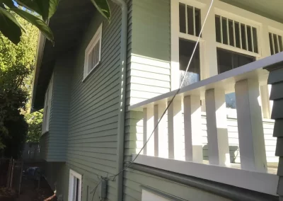 Exterior siding painting Redmond WA — sage green siding with crisp white porch railing