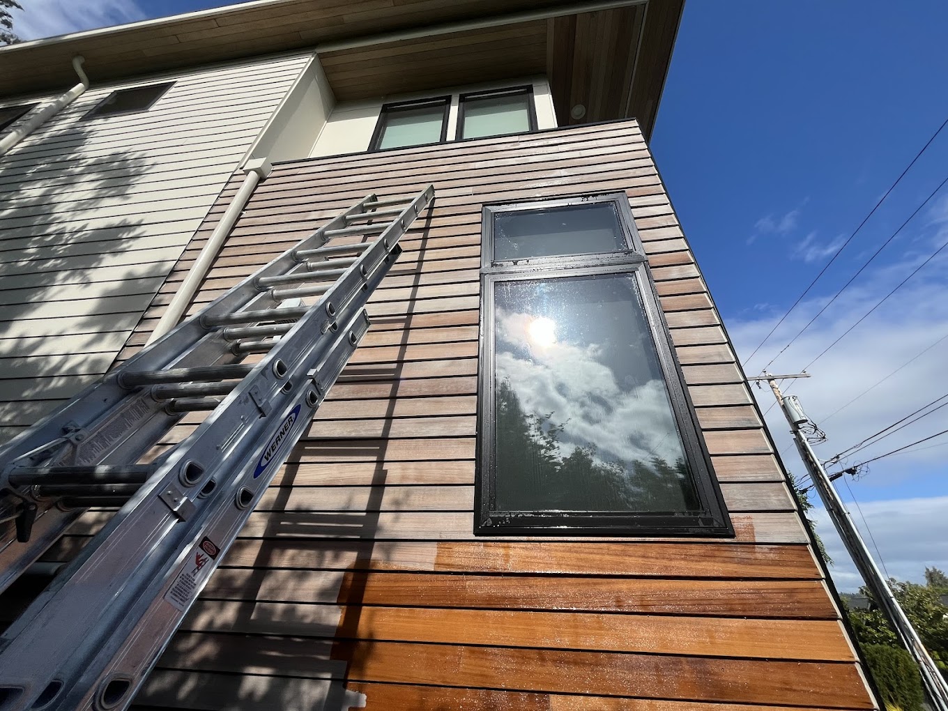 Exterior wood staining Redmond WA — modern home with horizontal cedar slat siding being restained, extension ladder in frame