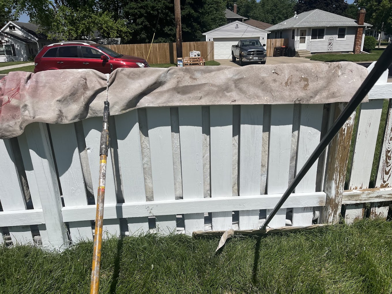 Fence painting Redmond WA — spray painting weathered wood fence fresh white in progress