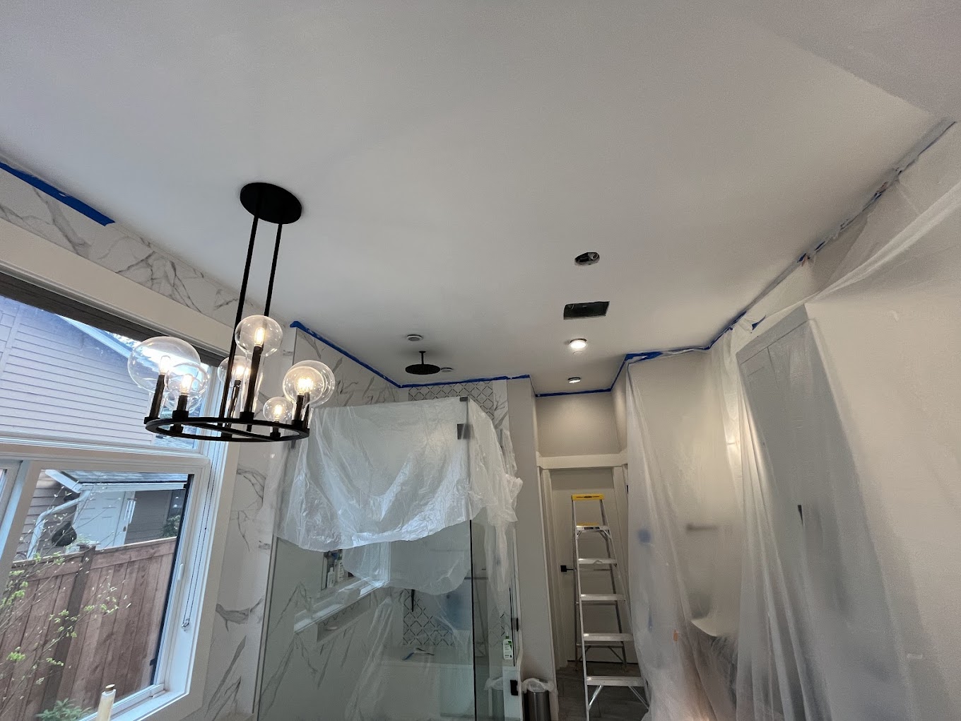 Interior painting prep Redmond WA — luxury bathroom masked off with blue tape and plastic before repaint
