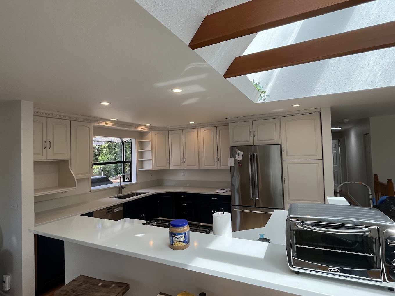 Kitchen remodel Redmond WA — cream upper cabinets and navy island in a vaulted skylit kitchen with white quartz counters