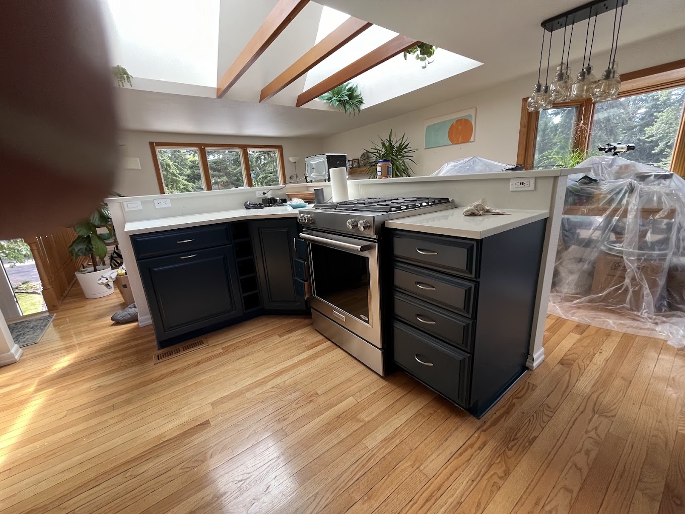 Kitchen remodel Redmond WA — wide view of skylit kitchen with navy island, hardwood floors and exposed beams