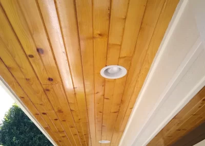 Wood ceiling varnish service Redmond WA — natural cedar tongue-and-groove porch soffit with recessed light