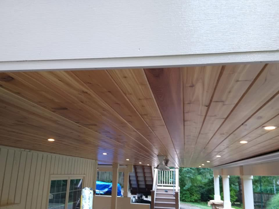 Wood ceiling varnish Redmond WA — cedar tongue-and-groove ceiling under deck with recessed lights and warm clear coat